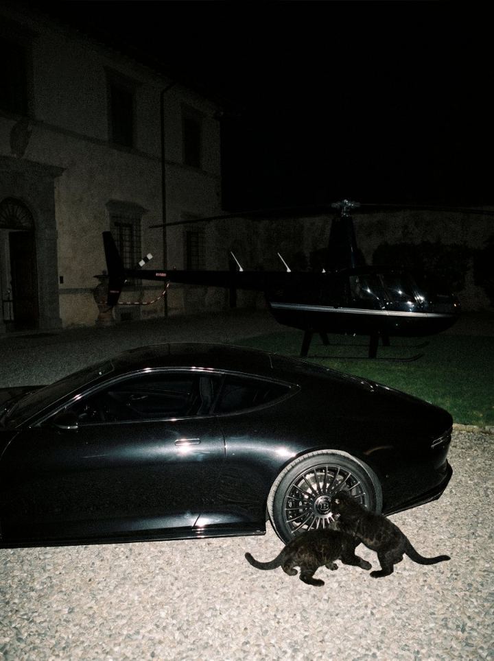 Black sports car at night with a helicopter behind it